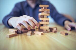 attività commerciale strategia concetto con mani giocando un' di legno bloccare Torre gioco, simboleggiante rischio e stabilità. pianificazione rischio gestione foto