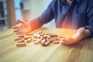 attività commerciale strategia concetto con mani giocando un' di legno bloccare Torre gioco, simboleggiante rischio e stabilità. pianificazione rischio gestione foto