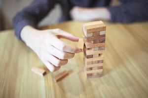 attività commerciale strategia concetto con mani giocando un' di legno bloccare Torre gioco, simboleggiante rischio e stabilità. pianificazione rischio gestione foto