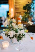 luminosa mazzo di fiori nel un' vaso sta su un' impostato tavolo foto