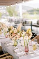 mazzi di fiori di fiori nel vasi In piedi su il festivo tavolo tra bicchieri e piatti foto