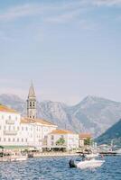 yacht è ormeggiato via il costa di perast prospiciente antico case e il campana Torre di il Chiesa di st. nicola. montenegro foto