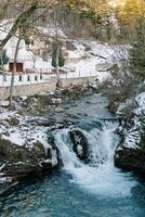 montagna cascata nel un' piccolo villaggio nel un' conifero foresta foto