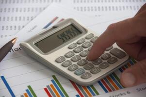 mano urgente calcolatrice con finanziario analisi carta. attività commerciale strategia e bilancio concetto foto