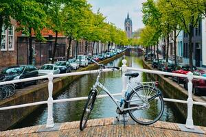 bicicletta su ponte e canale con macchine parcheggiata lungo e oude kerk vecchio Chiesa nel maiolica di delft strada foto