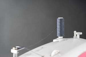 bobina di grigio cucire filo sta su superiore di un' bianca moderno cucire macchina foto