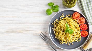 tradizionale italiano spaghetti pasta pesto e ingredienti nel nero piatto su bianca di legno sfondo foto