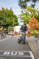 praga, ceco repubblica - ottobre 10, 2023. contento famiglia padre insegna bambino figlia per cavalcata pubblico bicicletta su uno di traffico terreno di gioco nel praga, ceco repubblica, Europa. alto qualità foto