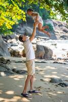 poco ragazza e sua padre avendo divertimento su riva del mare nel il ombra di alberi e palme. contento famiglia concetto. alto qualità foto
