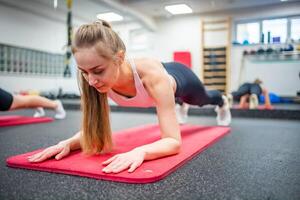 giovane sport donna fare esercizio nel un' tavola posizione per il addominali a palestra, lei esercizio per forte e bene sano. alto qualità foto