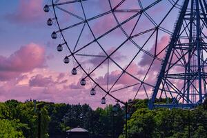 un' crepuscolo di Ferris ruota a il parco dietro a il blu cielo teleobiettivo tiro foto