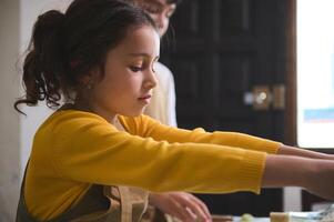 avvicinamento ritratto di un' poco capocuoco ragazza preparazione Ravioli durante cucinando maestro classe in casa foto