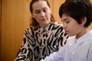 adolescente ragazzo pianista musicista praticante pianoforte, giocando classico melodia, seduta vicino il suo musica insegnante mentre un individuale lezione foto