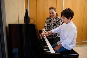 femmina musica insegnante spiegando pianoforte lezione per sua alunno durante individuale musica lezione a casa. musicale formazione scolastica e artistico sviluppo per giovane persone e bambini. Hobby e tempo libero foto