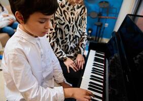 fiducioso talentuoso adolescenziale musicista giochi pianoforte forte, crea musica e canzone compone un' melodia durante musica lezione foto