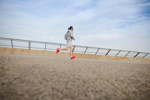 lato Visualizza giovane sportivo, maschio atleta in esecuzione su il città tapis roulant, godendo mattina jog su il lungomare di ponte foto