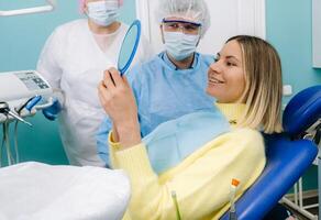 il dentista Spettacoli il cliente il risultati di il suo opera nel il specchio foto