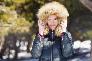giovane donna che indossa una giacca con cappuccio pelosa godendo le montagne innevate in inverno. foto