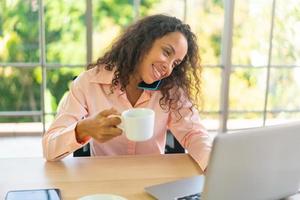 donna latina che lavora con una tazza di caffè sullo spazio di lavoro