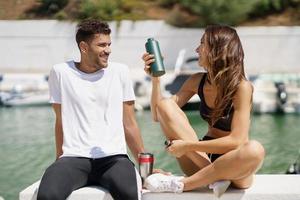 giovane coppia sportiva si idrata con acqua in lattine di metallo mentre si prende una pausa dopo lo sport.
