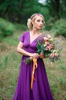 ragazza modella bionda in un abito lilla con un bouquet foto