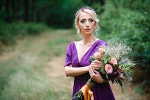 ragazza modella bionda in un abito lilla con un bouquet foto