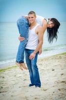 ragazzo e una ragazza in jeans e t-shirt bianche sulla spiaggia foto