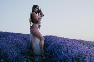 donna lavanda campo. contento spensierato donna nel beige vestito e cappello con grande orlo odorare un' fioritura lavanda su tramonto. Perfetto per ispirazione e caldo concetti nel viaggio e voglia di viaggiare. vicino su foto