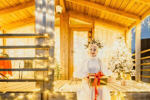 contento sorridente donna nel un' bianca vestito Tenere un' regalo scatola nel davanti di un' Natale albero. foto