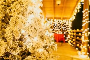 innevato Natale albero con luminosa bianca luci situato all'aperto vicino un' costruzione, un' accogliente festivo momento. foto