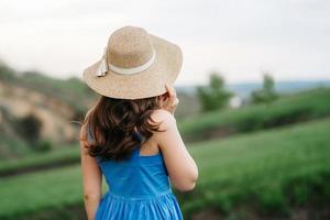 giovane ragazza con un cappello di paglia a tesa larga sui pendii della montagna foto