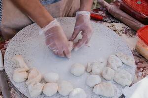 donna di mani fabbricazione qutab o chebureki con un' rotolamento perno e tritato carne cipolla nel Impasto per culinario concetti relazionato per azerbaigiano, tatar e greco cucina, come bene come empanadas nel latino America. foto