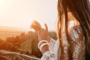 contento donna nel bianca boho vestito su tramonto nel montagne. romantico donna con lungo capelli in piedi con sua indietro su il tramonto nel natura nel estate con Aperto mani. silhouette. natura. tramonto. foto