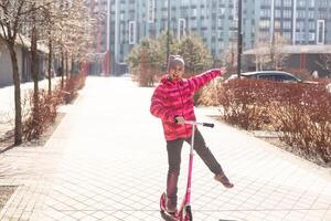 poco carino ragazza equitazione un' scooter su un' sentiero nel il parco foto