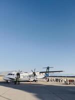 Podgorica, montenegro - 16 agosto 2023. persone con valigie In piedi nel linea su il pista di decollo per tavola il aereo foto