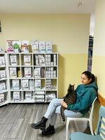 budva, montenegro - 25 dicembre 2022. giovane donna con un' soriano gatto su sua giro si siede su un' sedia nel un' veterinario clinica foto