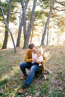 poco ragazza si siede su sua padre giro nel il foresta e giochi con ciottoli nel il suo mano foto