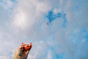 bobina di filo con un' aquilone volante nel un' nuvoloso cielo nel un' uomo mano foto