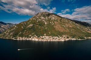 barca vele lungo il baia di kotor contro il fondale di il costa di perast a il piede di il montagne. montenegro. aereo Visualizza foto