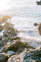 mare Surf rotoli al di sopra di il rocce nel il sole raggi foto