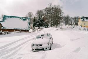 innevato auto sta nel un' cumulo di neve nel un' piccolo villaggio foto