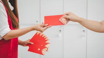 mani di Due persone partecipare nel il scambio di un' rosso Busta ornato con intricato oro modelli, un' costume simboleggiante bene auguri e fortuna nel asiatico tradizioni. foto