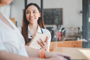 attento bar lavoratore assunzione un' cliente ordine, in mostra eccellente servizio con un' personale toccare nel un' moderno caffè negozio. foto