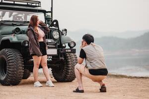 uomo cattura un' foto di un' donna in posa con fiducia Il prossimo per un fuori strada auto su un' panoramico sponde del lago.