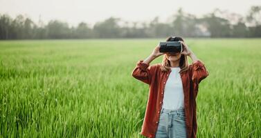 curioso donna regola sua vr cuffia, preparazione per tuffo in un' virtuale Esperienza nel il mezzo di un' vibrante, verde risaia campo. foto