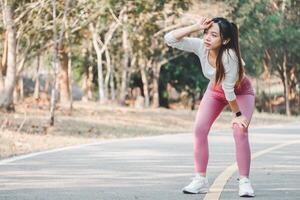 un' giovane atleta prende un' momento per freddo fuori uso, asciugandosi sudore a partire dal sua fronte dopo un' vigoroso allenarsi su un' parco sentiero, illustrare il importanza di riposo nel fitness regimi. foto