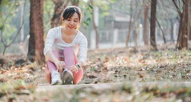 fitness e in esecuzione concetto, un' dettagliato Visualizza di un' donna nel rosa ghette legatura sua scarpa su un' pavimentata parco sentiero, messa a fuoco su Salute e fitness. foto