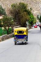ollantaytambo, Perù, 2015 - giallo e blu mototaxi andando giù strada Sud America foto