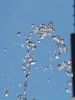 acqua gocce a partire dal Fontana andando su e caduta contro blu cielo foto