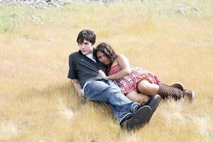 giovane adolescente coppia reclinabile all'aperto nel giallo erba foto
